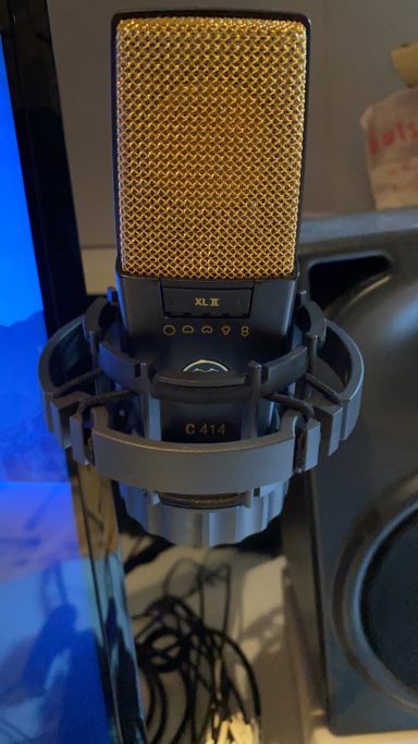 Schwarzes Mikrofon mit goldener Mikrofonmembran in Halterung. AKG 414